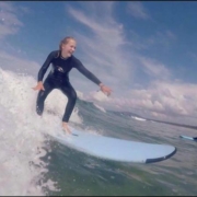 Surffailua Nuori nainen surffilaudalla aallonharjalla.