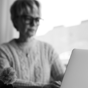 Tuija kirjoittaa läppärillä ikkunan edessä viikkopäiväkirjaa blogiin.