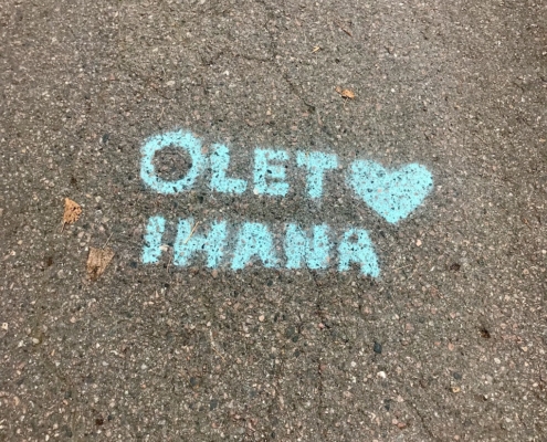 Turkoosi Olet ihana -teksti asfaltissa.