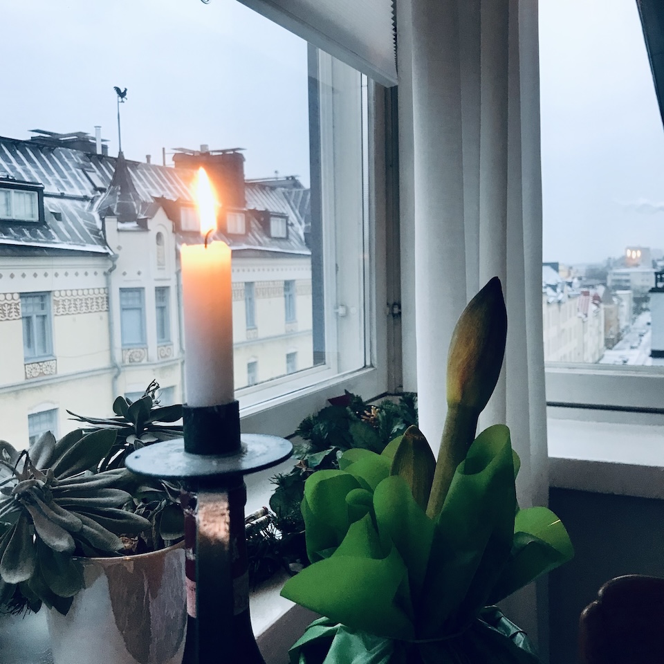 Kynttilä ja amaryllis kodin ikkunalaudalla.
