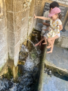 Lapset kastelevat jalkojaan vanhan kaupungin vuorilähteessä.