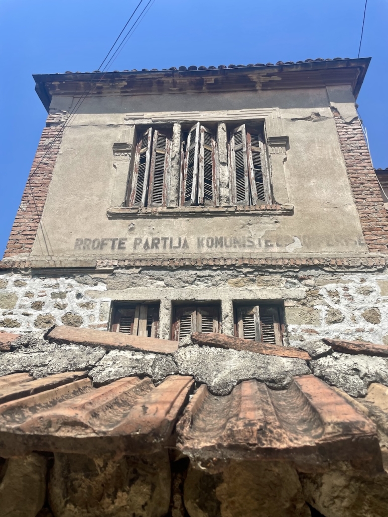 Albanialaisen talon seinässä näkyvä teksti "Kauan eläköön kommunismi".