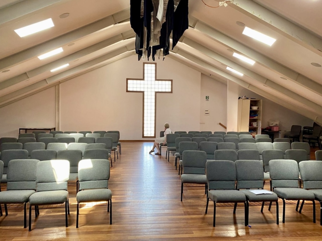 Seurakunnan seinällä valkoinen lasiristi.