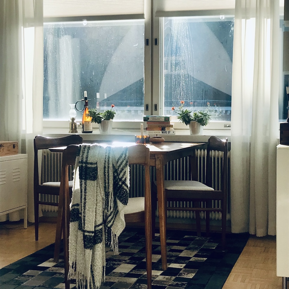 Ruokapöytä auringon paljastamien likaisten ikkunoiden äärellä.