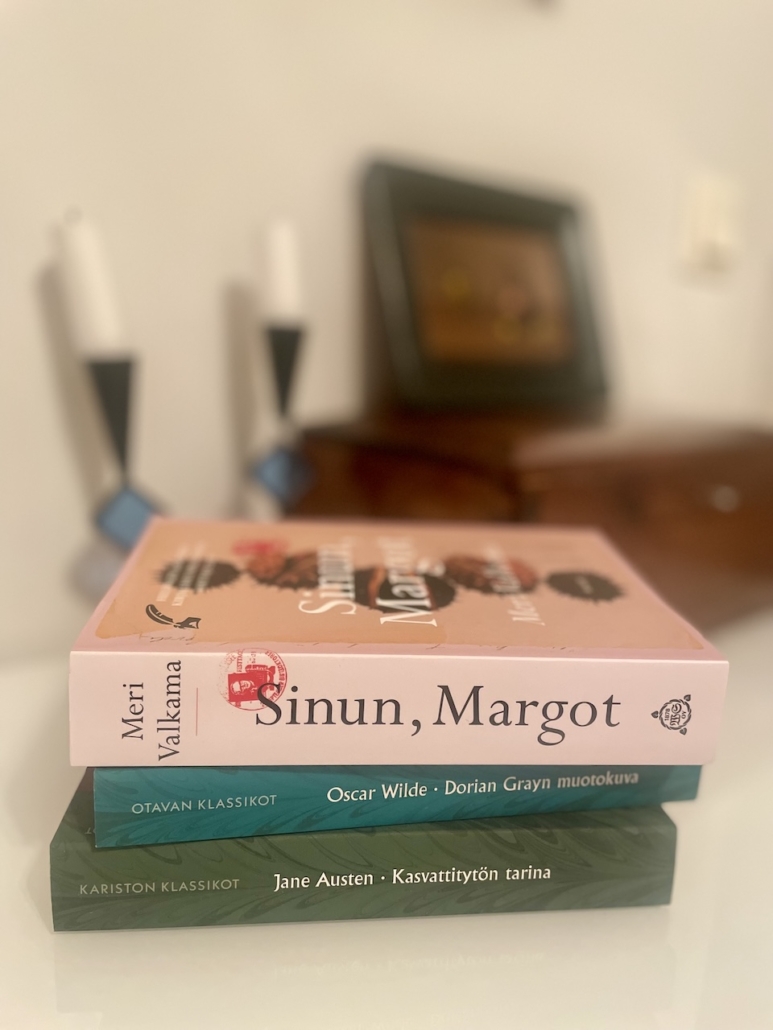 Kolme uutta kirjaa pinossa pöydällä.