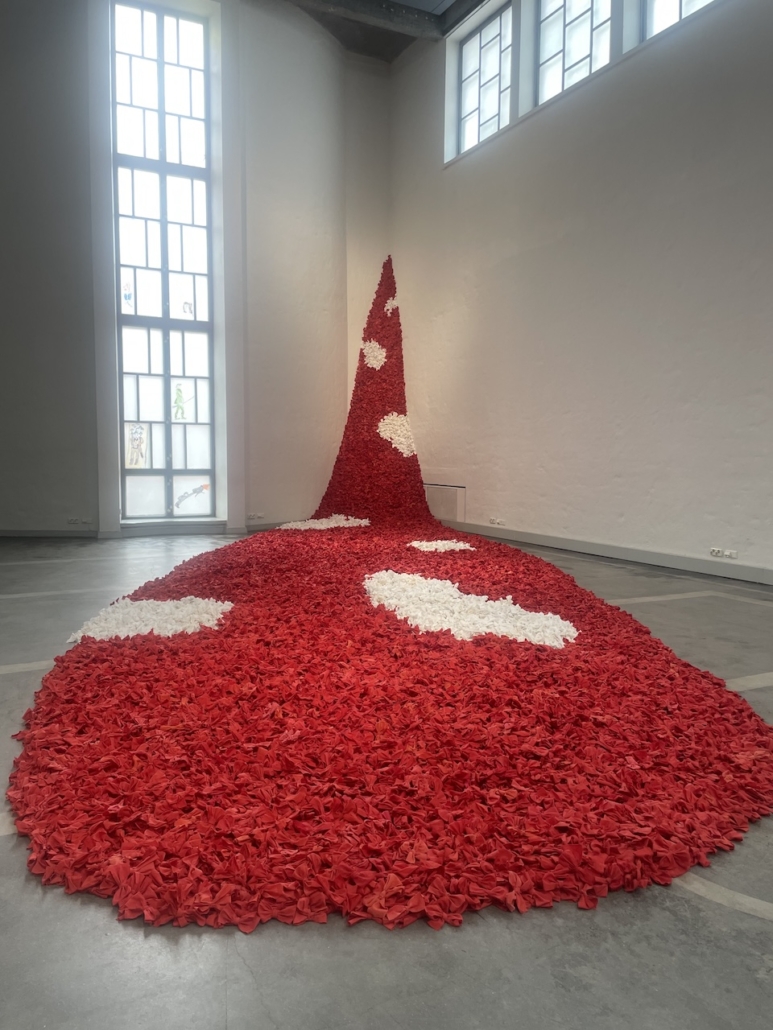 Taidehallin näyttelyn punavalkoinen tekstiiliteos.