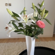 Äitienpäiväkukat Äitienpäivälahjaksi saadut liljat ja ruusu valkoisessa maljakossa.