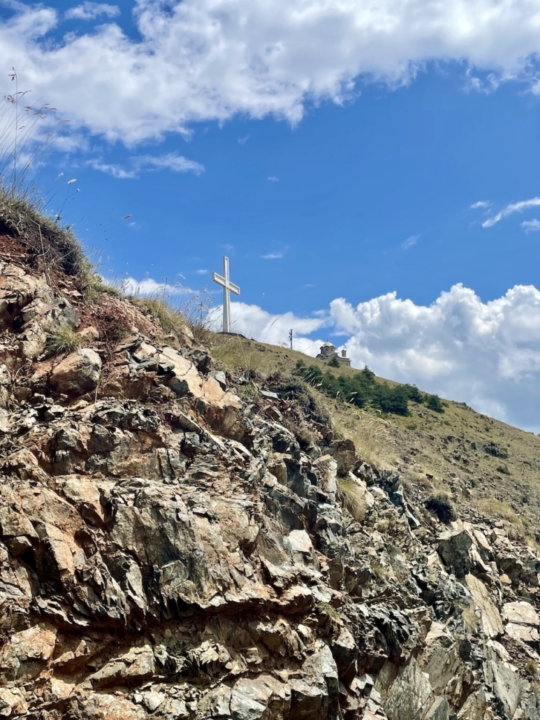 Morava-vuoren jyrkkä rinne ja rinteellä seisova valkoinen iso risti.