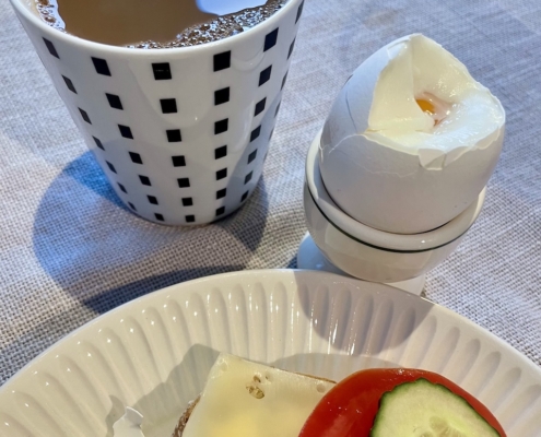 Kahvia, kananmunaa ja tomaattileipää aamiaispöydässä.