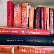 Oranssi- ja punakantisia kirjoja hyllyssä.