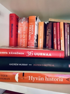 Oranssi- ja punakantisia kirjoja hyllyssä.