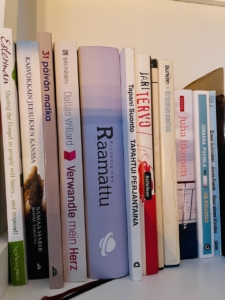 Kirjavakantiset kirjat hyllyssä.