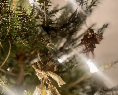 Kultaiset kellot ja enkeli joulukuusen oksalla.