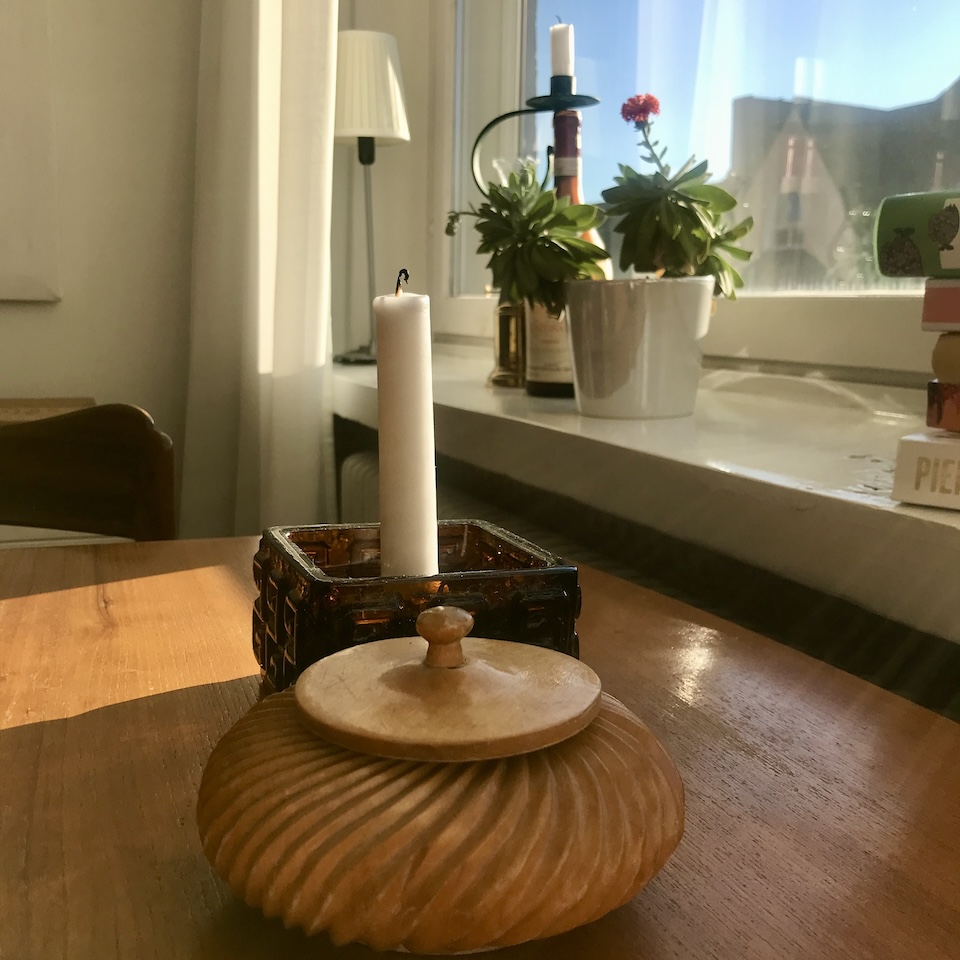 Taalari-kynttilänjalka ja puinen rasia tiikkipöydällä.