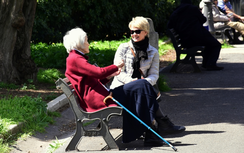 Minä ja vanha rouva keskustelemassa puistonpenkillä Roomassa.