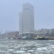 Korkea hotellirakennus ja meri jossa jäälautat kelluvat.