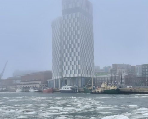 Korkea hotellirakennus ja meri jossa jäälautat kelluvat.