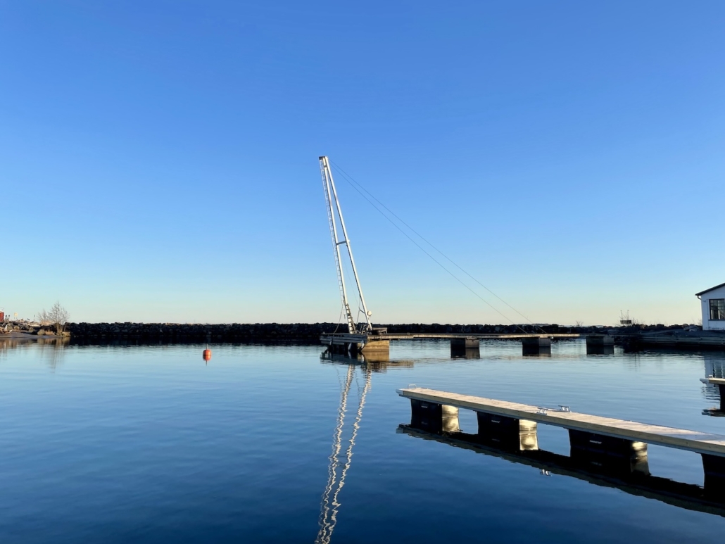 Tyyni meri ja pieni nostokurki satamassa.