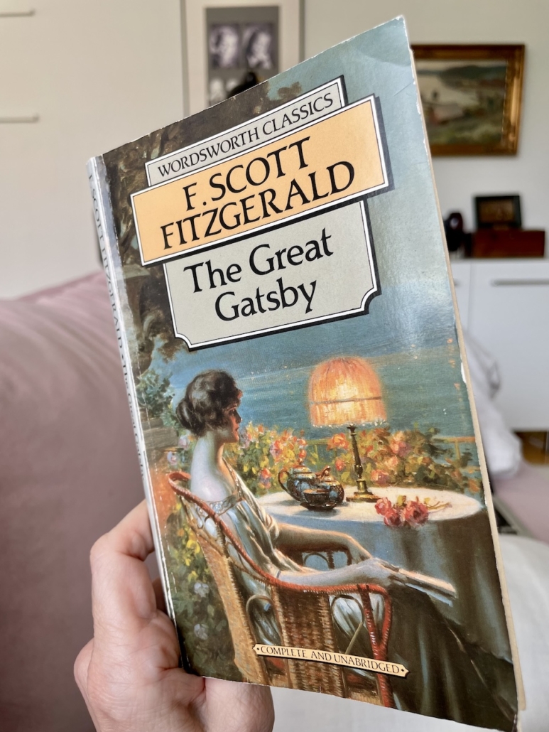 Kirjan The Great Gatsby kansi kädessäni sohvalla.