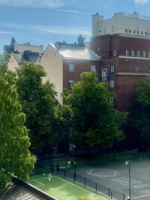 Kerrostaloja ja niiden väliin jäävä koulun pallokenttä.