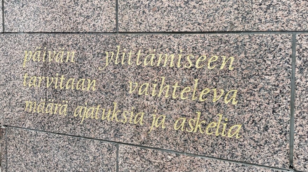 Seinämuuriin kirjoitettu teksti Päivän ylittämiseen tarvitaan vaihteleva määrä ajatuksia ja askelia.