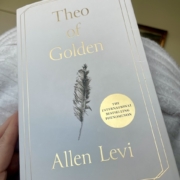 Kirjan Theo of Golden valkoinen kansi, jossa on musta piirretty sulka ja kullanväriset tekstit.