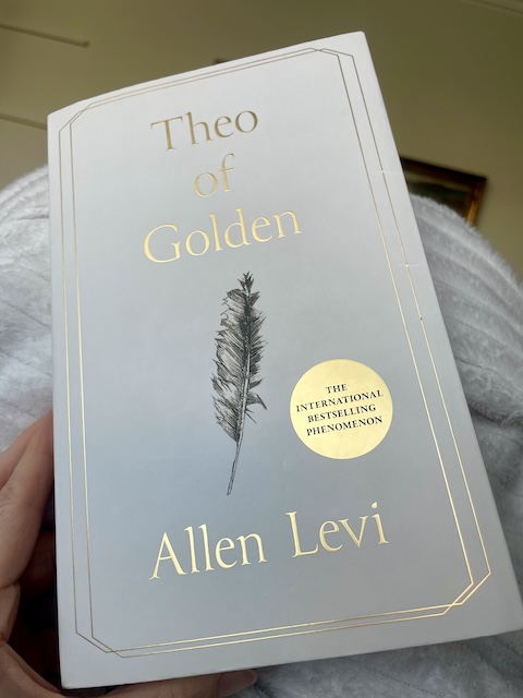 Kirjan Theo of Golden valkoinen kansi, jossa on musta piirretty sulka ja kullanväriset tekstit.