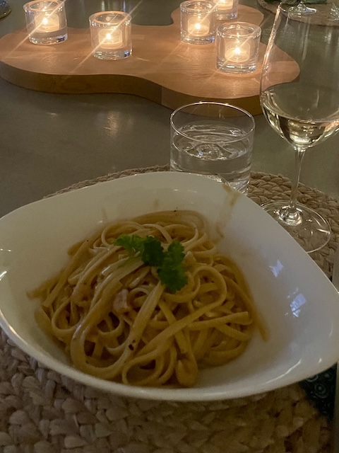 Katkarapupastaa lautasella ja taustalla tuikkukynttilöitä.